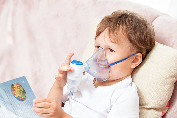 Boy making inhalation with a nebulizer at home