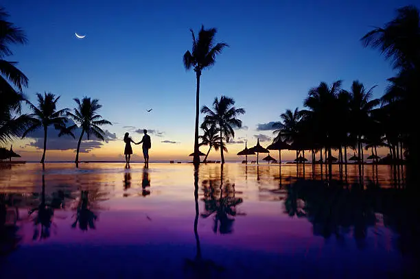 Photo of Silhouettes of young couple at scenic sunset