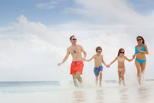 istock family running splashing water beach 621686054