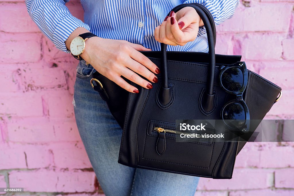 Close up black leather bag in hand of fashion woman. Close up of black leather handbag in hand of stylish woman. Female fashion and accessories. Women Stock Photo