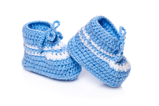 Homemade knitted baby blue booties isolated on white background