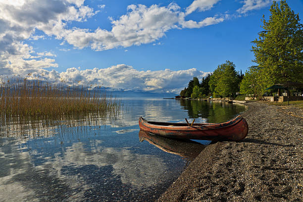 Two motor boats are standing on a flat sandy beach near the water. On the other bank you can see a series of forest islands, the water is smooth and calm.