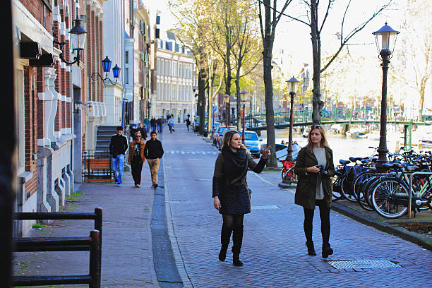 Amsterdam, Netherlands - May 1, 2016: Street view from the city center. Spring shot of people, tourists and two girl walking along city center of Amsterdam. 