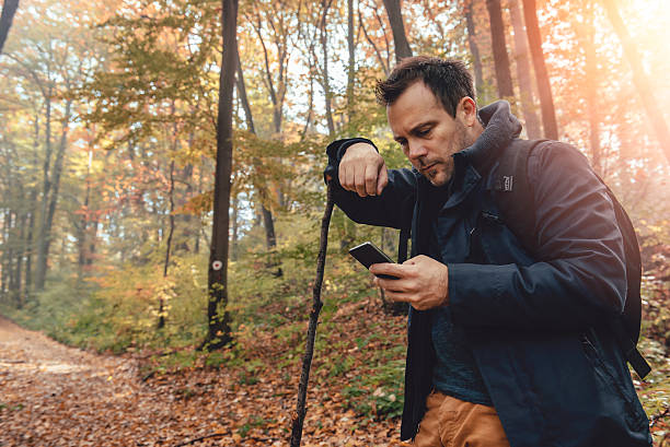 istock Man hiking in forest and using phone 621692498