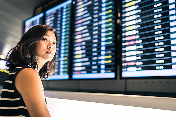 piękna azjatka podróżniczka na ekranie informacji o locie - commercial airplane airport arrival departure board business travel zdjęcia i obrazy z banku zdjęć