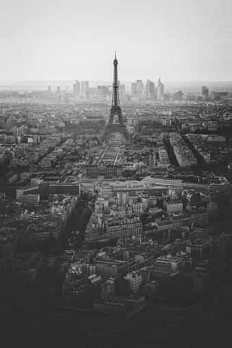 View, in black and white, over central Paris, with the Eiffel tower in the distance, and La Defense business district beyond.