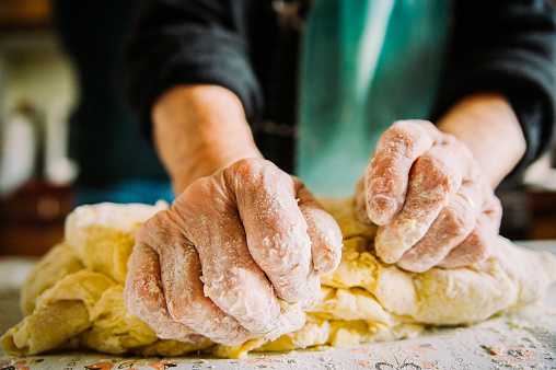 wrinkled hands making pasta for bread in traditional way