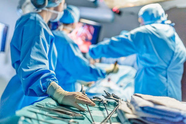 Surgeons in full surgical gear during operation Surgeon with his team in the operating room. surgery stock pictures, royalty-free photos & images
