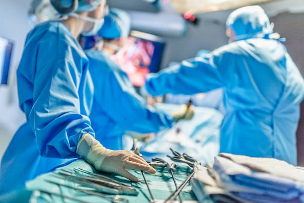 surgeons in full surgical gear during operation - operação imagens e fotografias de stock