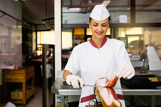 istock Pretty butchery woman cutting ham. 621702568