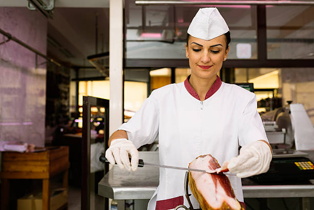 istock Pretty butchery woman cutting ham. 621702610