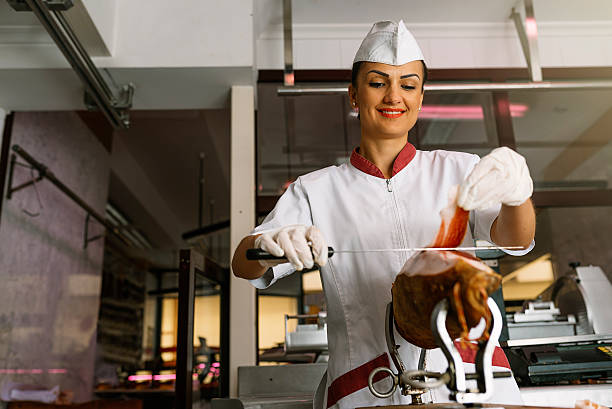istock Pretty butchery woman cutting ham. 621702620