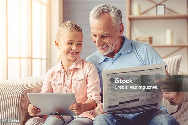 Grandpa And Little Girl At Home Stock Photo - Download Image Now - Newspaper, Reading, Digital Tablet