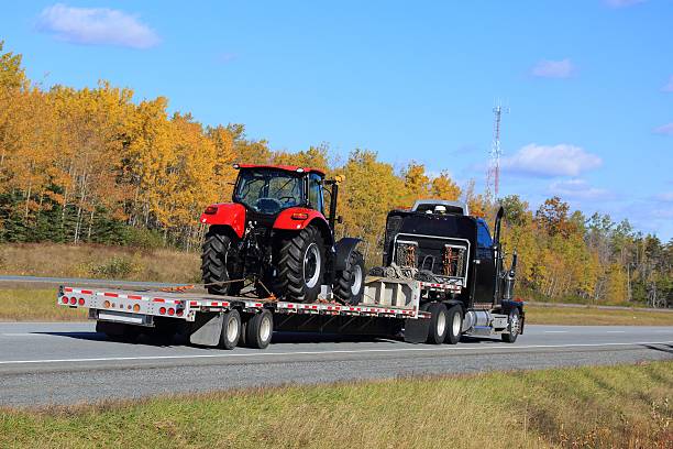 New tractor on a semi truck trailer New tractor on a flatbed trailer, being delivered by a semi truck. agricultural equipment stock pictures, royalty-free photos & images