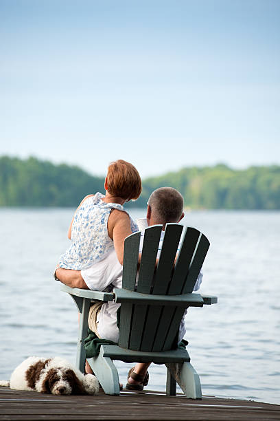 Couple on Pier Morning Coffee Couple having private moment on Pier with their pet dog and morning coffee. cottage life stock pictures, royalty-free photos & images