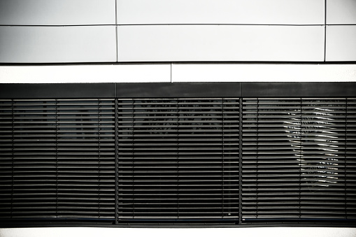 The facade of a modern office building with blinds in the windows.