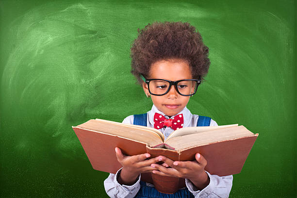 istock Schoolboy reading a book in front of school board 621714388