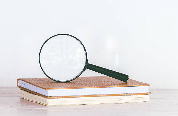 istock Magnifying glass and books on wooden table 621716478