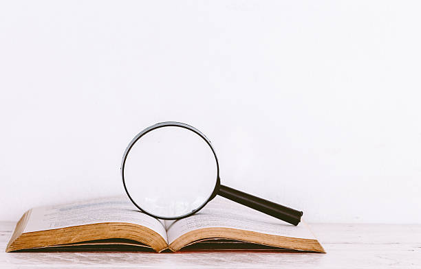 istock Magnifying glass and books on wooden table 621716510