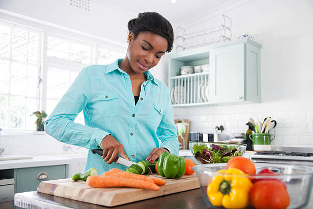 African female cooking up a storm. African female in the kitchen chopping a cucumber for her lunch that she's busy preparing. Cape Town, Western Cape, South Africa. african ethnicity south africa fitness stock pictures, royalty-free photos & images