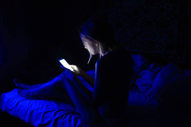 mujeres jóvenes que usan el teléfono inteligente en la cama antes de dormir - working bed smart phone bedroom fotografías e imágenes de stock