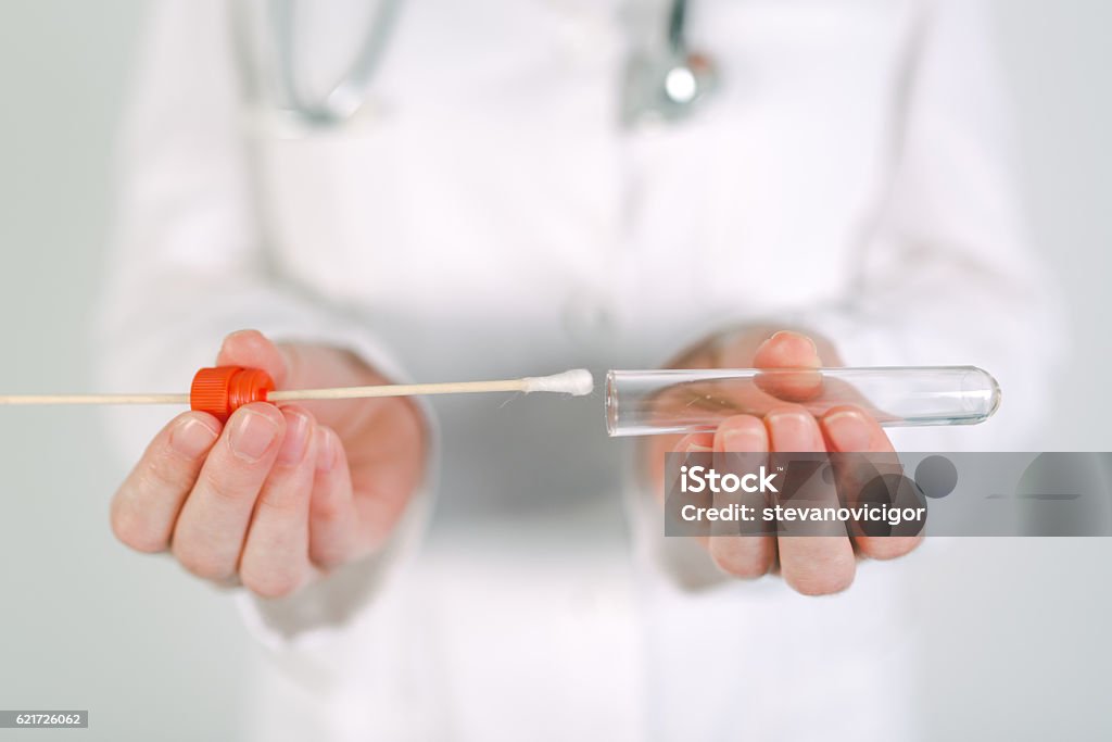 Female forensic technician collecting biological specimen in DNA Female forensic technician collecting biological specimen in DNA tube, close up of womans hands in white uniform with sampled cotton swab Cotton Swab Stock Photo
