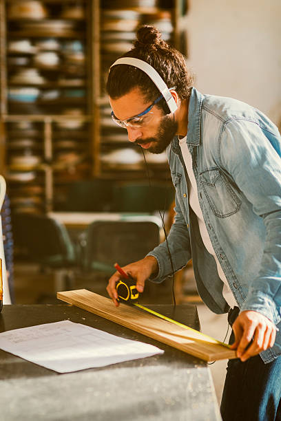 istock Male Carpenter Measuring Plank In His Workshop 621727600