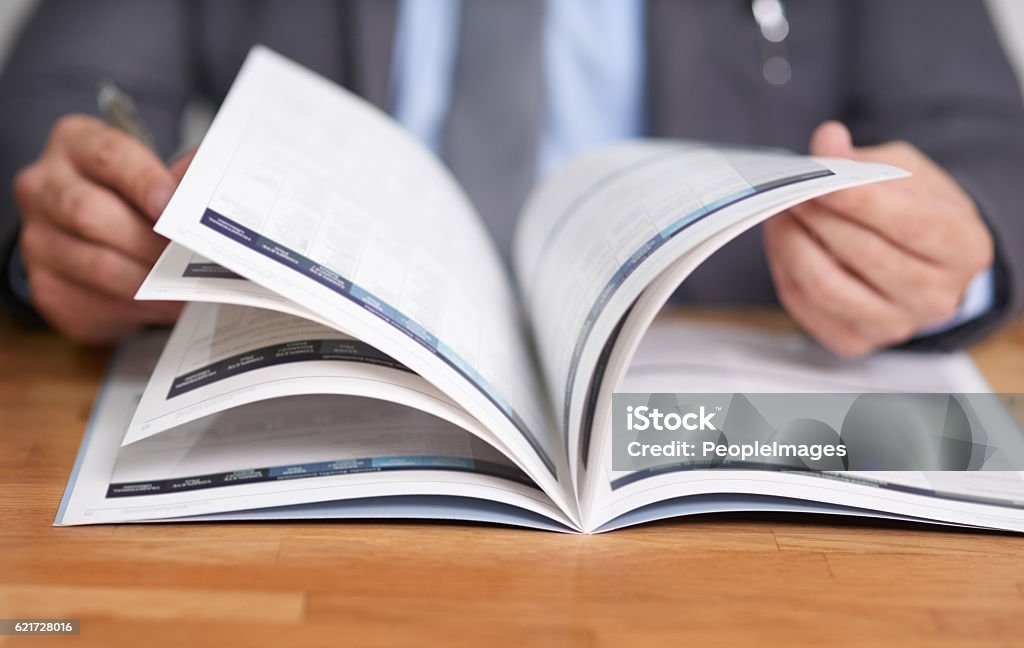 Keeping informed is the key to success Cropped shot of an unidentifiable man reading a book Brochure Stock Photo