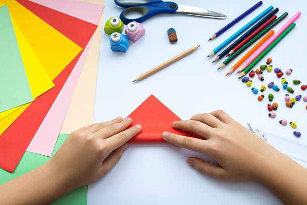 istock Children's hands do origami  bird from red paper. 621728326