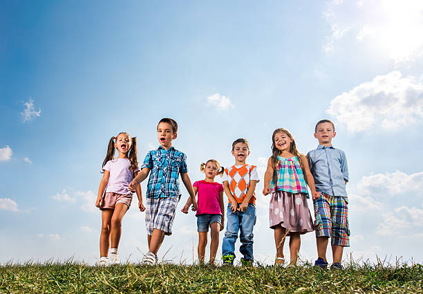 istock Below view of cute kids walking in a meadow. 621729094