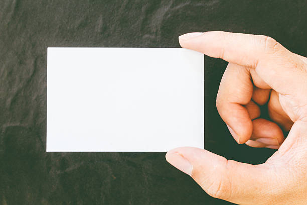 istock Hands holding blank business card on black background 621732204