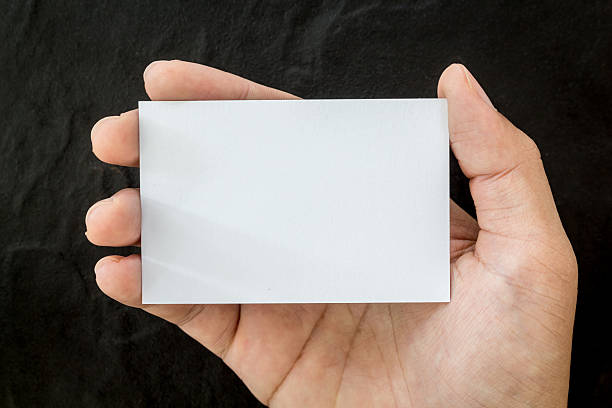 istock Hands holding blank business card on black background 621732410