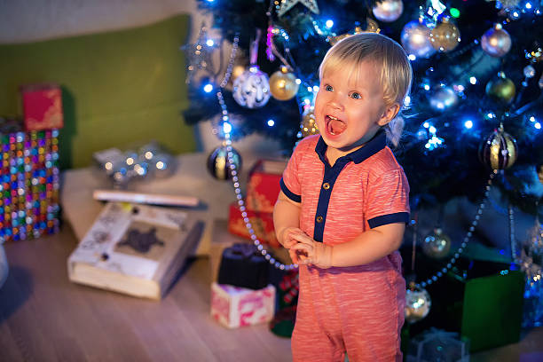 Christmas concept. Little baby boy decorates the Christmas tree stock photo