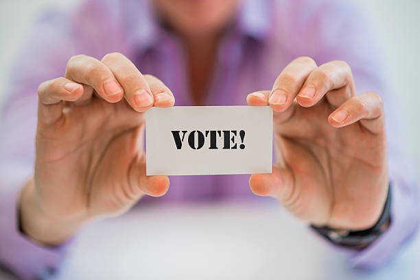 istock Man holding card with a message written on it: Vote 621816792