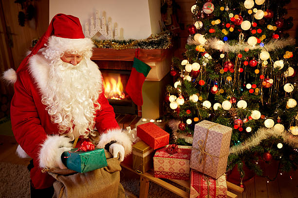istock Santa Claus in wooden home interior with gift boxes 621818270