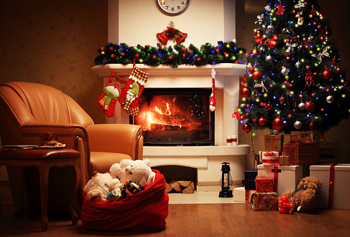 Christmas Tree and Christmas gift boxes in the interior with a fireplace. Christmas living room with fireplace and armchair