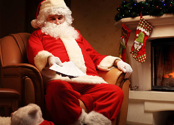 istock Santa sitting at the Christmas tree, holding Christmas letters 621818802
