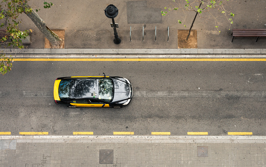 Barcelona, Spain - September 30, 2016: Motion blur on a black and yellow taxi, being driven along a sidestreet in Barcelona, photographed from directly above.