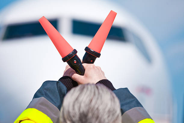 Air traffic controler holding signals Back view of air traffic controler holding signals. Aircraft in the background.  air traffic control operator stock pictures, royalty-free photos & images