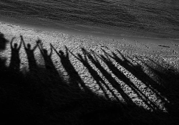 istock Shadows of people with arms raised on a beach 621820576