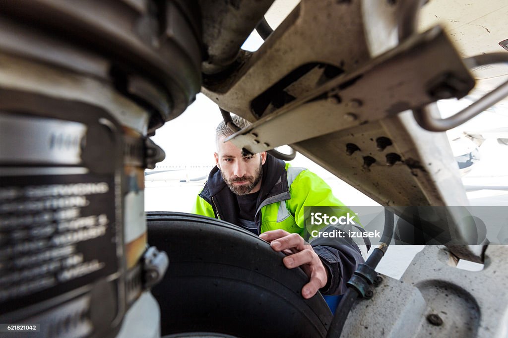 Airport worker checking tires Airport worker chcecking aircraft chassis. Close up. Repairing Stock Photo