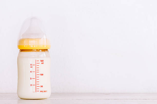 istock Baby bottle with milk  on wooden table 621821376