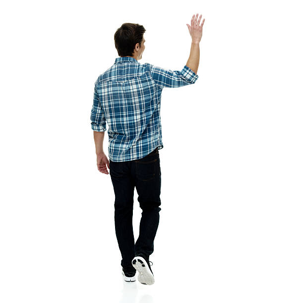 istock Rear view of man waving hand and walking 621821842