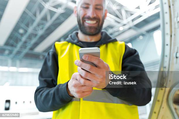 Aircraft Engineer Using A Smart Phone In A Hangar Stock Photo - Download Image Now - Engineer, Air Vehicle, Mobile Phone