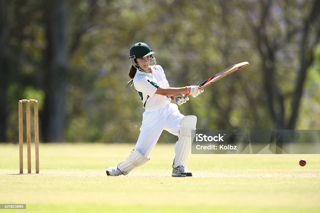 Female Cricketer Batting A young girl plays a shot while batting in a game of cricket Sport of Cricket Stock Photo