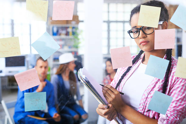 istock Young african woman reading post-it notes on glass wall 621824006