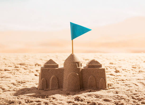 istock Sand castle with flag on the sea shore. 621824110