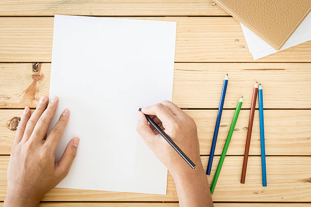 istock Hands drawing on  paper on wooden table background 621825242