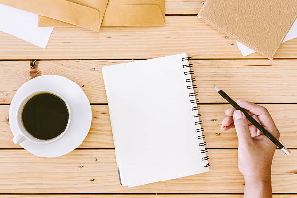 istock Hands writing on a wooden table with office supplies 621825334