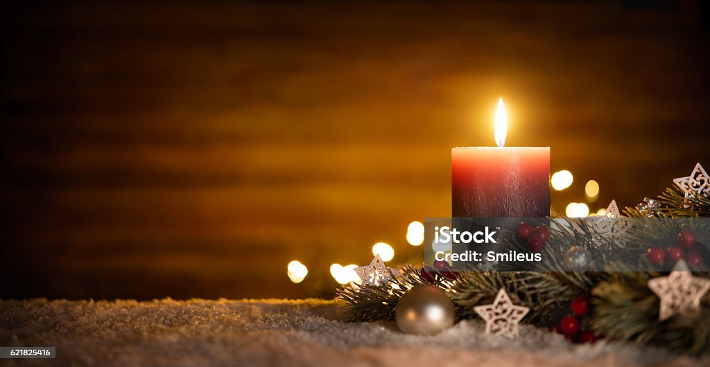 Candle and Christmas decoration with wooden background Burning candle and Christmas decoration over snow and wooden background, elegant low-key shot with festive mood Candle Stock Photo